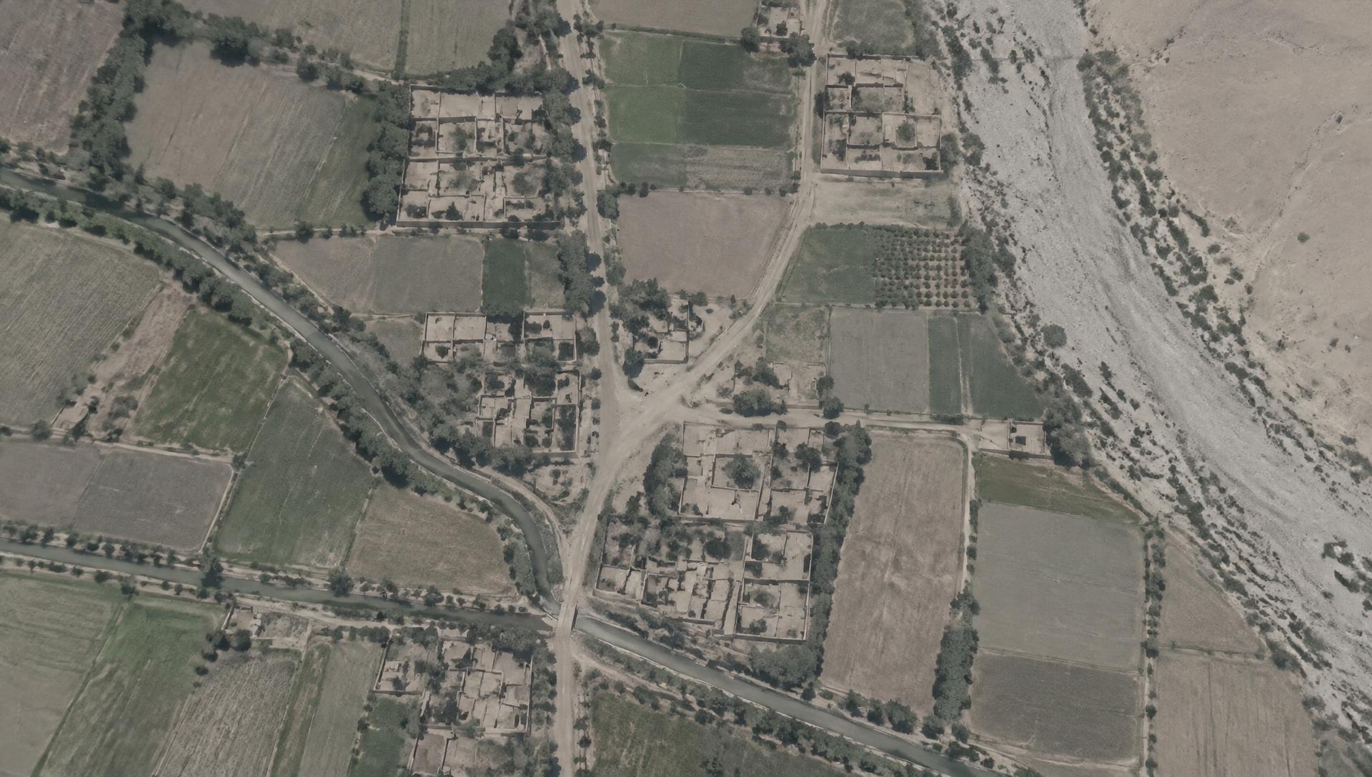 Degraded overhead surveillance view of compounds, fields and tracks